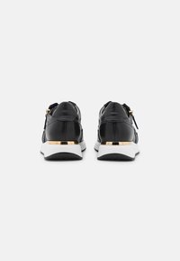 Sneakers in pelle nera con finitura liscia, suola bianca e dettaglio dorato sul tallone. Presentano una chiusura con zip e lacci per una facile vestibilità.