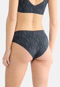 Fekete bikini alsó, fehér pöttyös mintával, közepesen magas derékkal, sima anyagból és varrás nélküli kidolgozással.