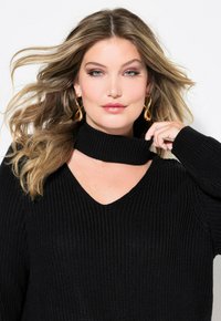 Schwarzer Strickpullover mit V-Ausschnitt und Rippstruktur, der einen hohen Kragen hat. Lange Ärmel und eine lockere Passform vervollständigen das Design.