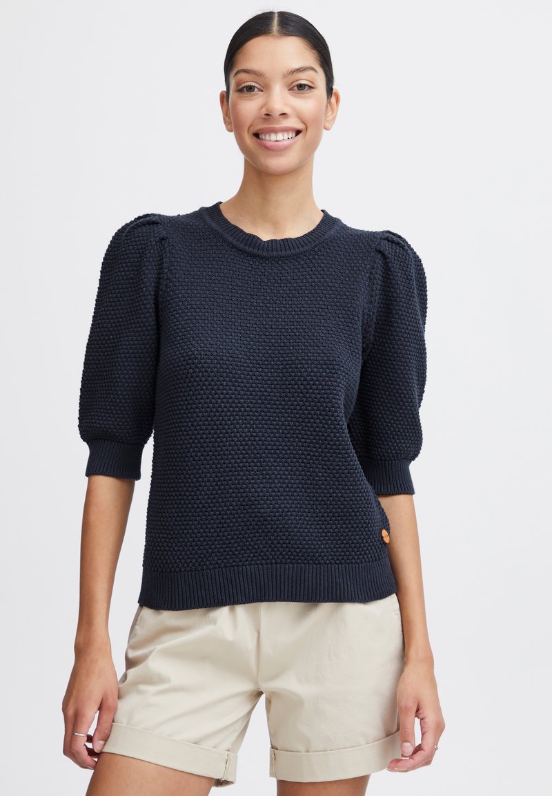 Marineblauer Strickpullover mit strukturiertem Stoff, rundem Ausschnitt, puffierten kurzen Ärmeln und geripptem Saum. Mit einem kleinen orangen Logodetail an der Seite.