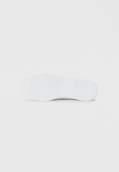 Talpa de sneaker albă cu o prindere din cauciuc texturat și detalii cu un logo circular. Suprafața are un model pentru aderență și durabilitate.