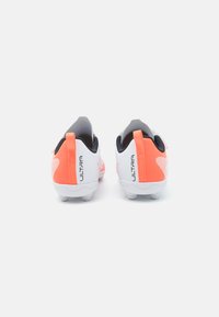 Chaussures de football rouges et blanches au design épuré, dotées d'une tige texturée, d'accents noirs et d'un logo "ULTRA" bien en vue sur le talon.