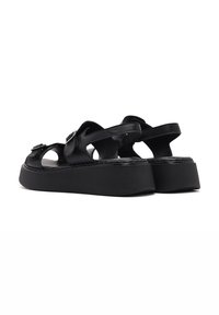 Black platform sandals featuring cut-out design, smooth leather material, adjustable straps, and a textured rubber sole for grip.