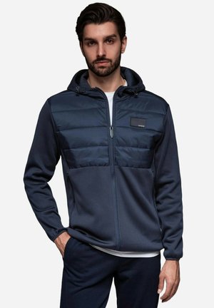 Marinefarbener Kapuzenjacke mit gesteppter Oberfläche und strukturiertem unteren Gewebe, ausgestattet mit einem Frontreißverschluss und einem kleinen Logopatch.