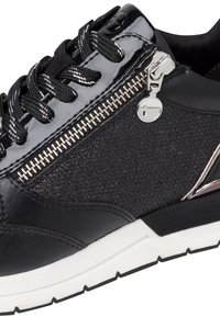 Baskets noires avec fermeture éclair argentée et tirette ronde, panneau latéral en tissu texturé, lacets noirs avec accents blancs, et semelle blanche.