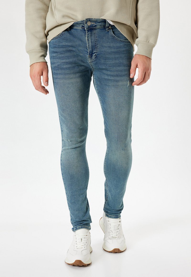 Jeans skinny blu chiaro in denim, con un lavaggio sbiadito, quattro tasche e chiusura con bottone in vita.