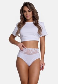 Witte cropped t-shirt gecombineerd met witte high-waisted panties met een sheer kanten tailleband en bloemmotief. Gladde katoentextuur.