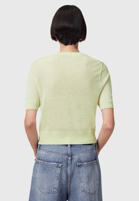Mintgroene gebreide trui met korte mouwen, geribde zoom en naadloze schouders. Draagt bij hoge taille denim shorts.