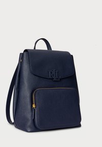 Σακίδιο από navy δέρμα με υφή, κλείσιμο με μαγνητικό καπάκι, μπροστινή τσέπη με φερμουάρ και χρυσές λεπτομέρειες.