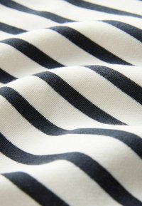 Tela de algodón con franjas alternas en negro y blanco, que muestra una textura suave y ondas ligeras.