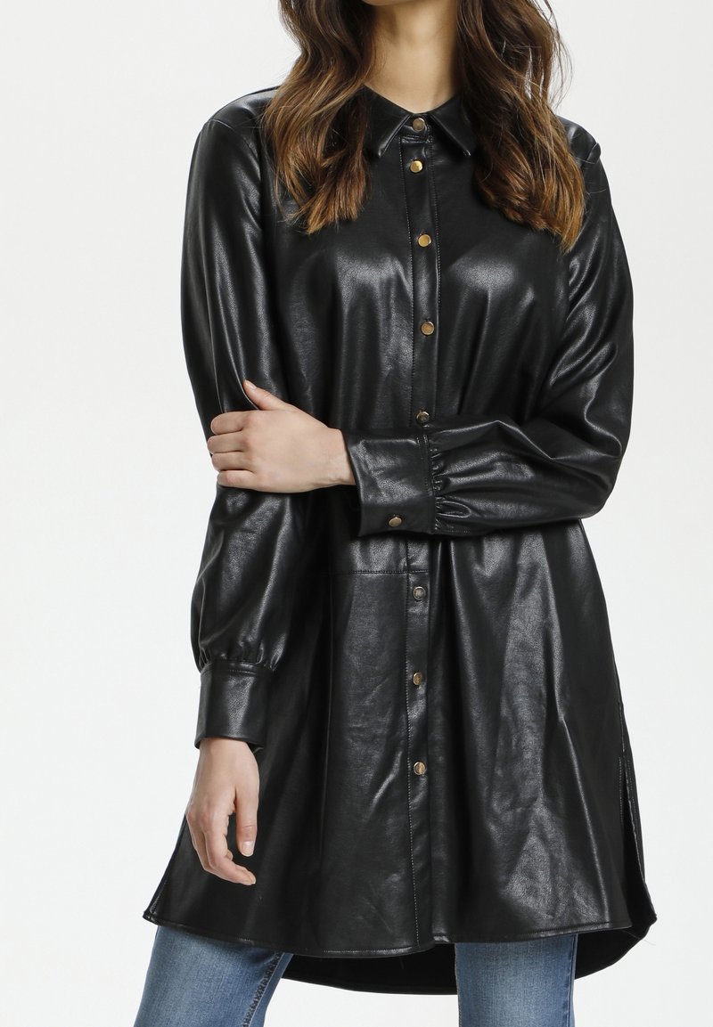 Abito camicia in finta pelle nera con colletto, chiusura a bottoni, maniche lunghe e spacchi laterali, caratterizzato da una texture lucida e dettagli in oro.