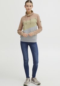 Felpa a blocchi di colore con colletto alto; presenta pannelli beige, crema e grigio. Tessuto morbido, accenti con cordino e polsini a coste.