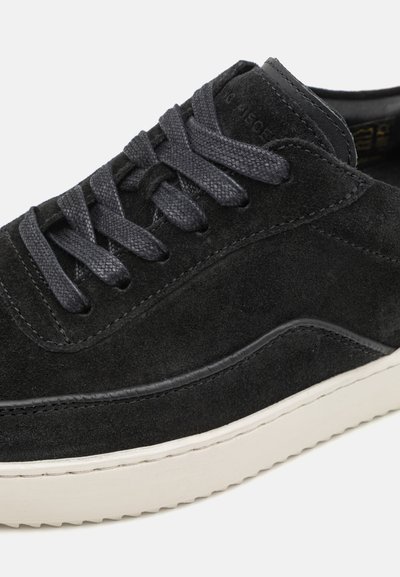 Mustat mokkanahka sneakerit, joissa on tekstuuripinta, tummat nauhat ja kontrastiväri valkoinen kumipohja. Pyöristetty muoto ja pelkistetyt muotoiluelementit.