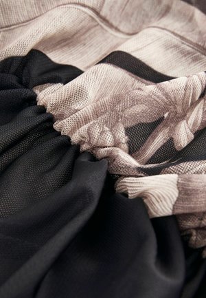 Zwart en beige verzameld stof met bloemenpatronen, met verschillende texturen; het gladde zwarte materiaal contrasteert met de zachte beige details.