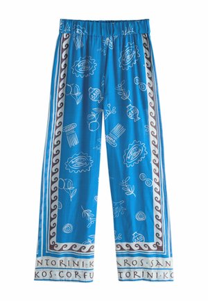 Niebieskie spodnie o szerokich nogawkach z białymi, greckimi wzorami, brązową falistą bordiurą i nazwami miast nadrukowanymi wzdłuż nogawki.