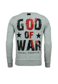 Grijze trui met opvallende zwarte en rode tekst "GOD OF WAR" met zwarte sterren en spetters. Geribbelde boorden en zoom. Gemaakt van katoen.