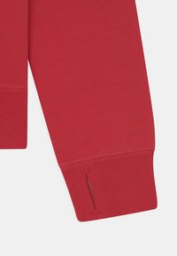 Manche de sweat-shirt rouge avec un poignet à fente et un tissu texturé. Cousu avec précision et terminé par des coutures nettes.