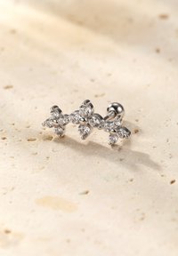 Srebrny klips do ucha z wieloma przezroczystymi cyrkoniami ułożonymi w kwiatowy wzór. Gładkie metaliczne wykończenie z gwintowanym prętem do mocowania.