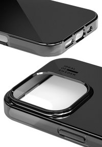 Funda de teléfono negra transparente con bordes redondeados, que muestra un corte cuadrado para la cámara, marcado con el texto "IDEAL OF SWEDEN". Textura suave.