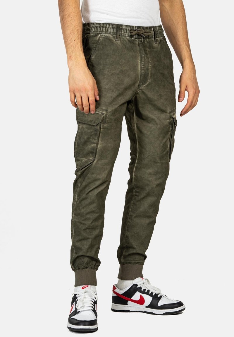 Olivgrüne Cargo-Hosen mit elastischem Bund, seitlichen Taschen und schmal zulaufenden Säumen; aus einem Baumwollmix mit weich strukturierter Oberfläche.