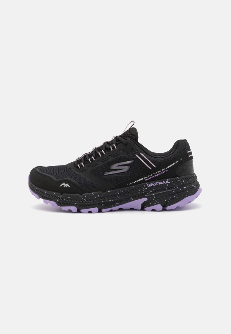 Chaussures de sport noires avec une tige en mesh respirant, une semelle intermédiaire parsemée de violet et une semelle extérieure rembourrée. Elles comprennent des accents réfléchissants et des lacets.