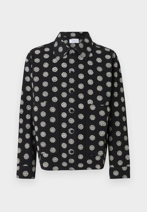 Chaqueta negra abotonada con patrones florales circulares blancos, mangas largas, dos bolsillos frontales y cuello puntiagudo.