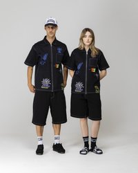 Black collared shirts with colorful embroidered designs, paired with black shorts. Accessories include a white cap and various footwear styles.