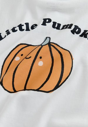 Camisa de algodón blanca con un gráfico de una calabaza naranja con contornos negros, detalles faciales sonrientes y el texto "Pequeña Calabaza".