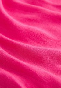 Ljust rosa tyg med en slät, strukturerad yta, som visar mjuka veck och vågor, vilket indikerar ett lätt material.