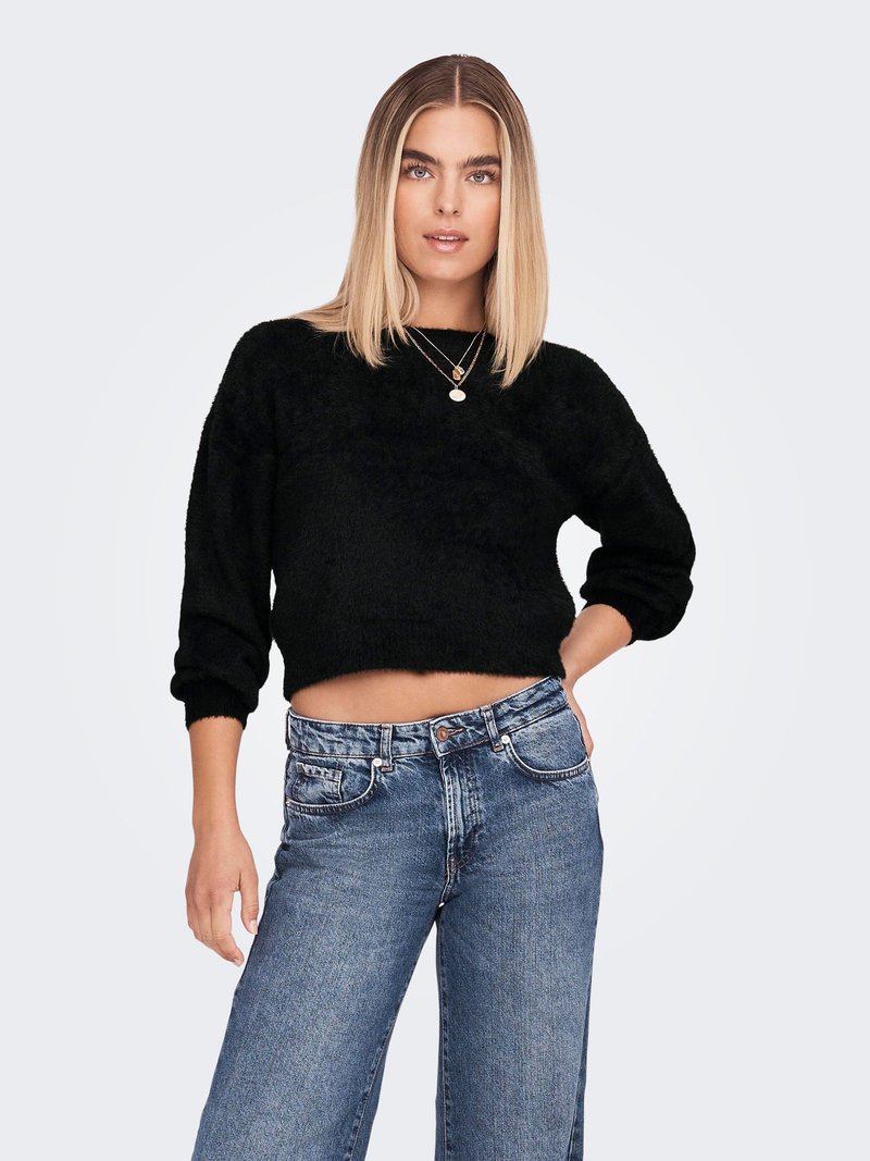 Black cropped sweater in soft, textured fabric paired with high-waisted, faded blue denim jeans featuring a button closure and side pockets.