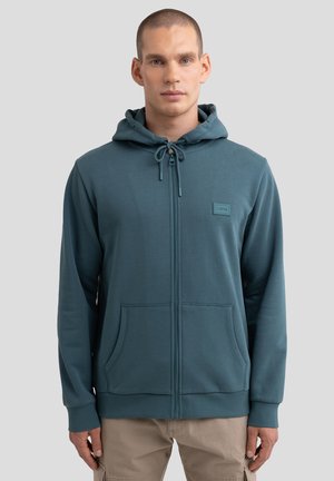 Kapuzensweatshirt mit Reißverschluss aus türkisfarbenem Stoff, ausgestattet mit einer Fronttasche, Kordelzug und einem kleinen Logopatch auf der Brust. Glatte Textur.