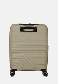 Valigia rigida beige con finitura testurizzata. Dotata di maniglia superiore, chiusura con zip e quattro ruote per una facile manovrabilità.