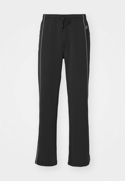 Pantalons de survêtement noirs avec taille à cordon, en matériau doux, dotés de bandes latérales blanches contrastantes et d'un design de jambes légèrement évasées.