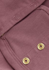 Lila tyg med en slät yta har guldmetallringar. Tyget har en fin stickning och tätt placerade stygn längs kanten.