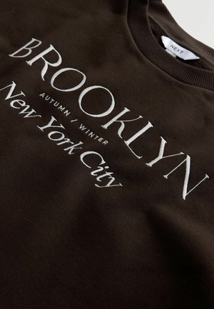 Brauner Sweatshirt mit weißem Text: "BROOKLYN HERBST / WINTER New York City", mit Rundhalsausschnitt und weicher Textur.