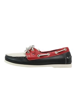 Chaussure bateau en cuir pour homme en noir, blanc et rouge avec des lacets blancs et des détails de marque sur la semelle et le panneau latéral.