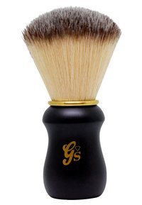 Svart handtagsrakborste med en böjd form, med en guldaccent och mjuka borst som övergår från ljus till mörk. Logotyp synlig.