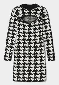 Långärmad, figurnära klänning med ett svartvitt hundtandsmönster, texturerad stickad kvalitet och en utskärning i triangelform vid bröstet.