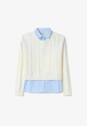 Suéter color crema de punto trenzado, superpuesto sobre una camisa de rayas azul claro con cuello. El suéter presenta un patrón de diamantes y un dobladillo acanalado.