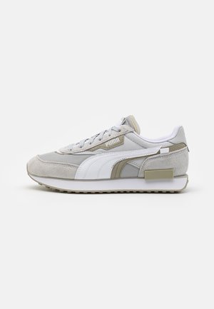 Baskets Puma grises et blanches avec panneaux en daim et tissu, bande avec logo Puma blanc, fermeture à lacets sur fond blanc.