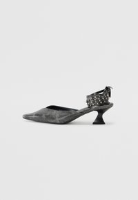 Sandal noir texturé à talon ouvert avec un bout pointu et un talon incurvé. Équipé de clous métalliques sur la bride de cheville pour un détail supplémentaire.