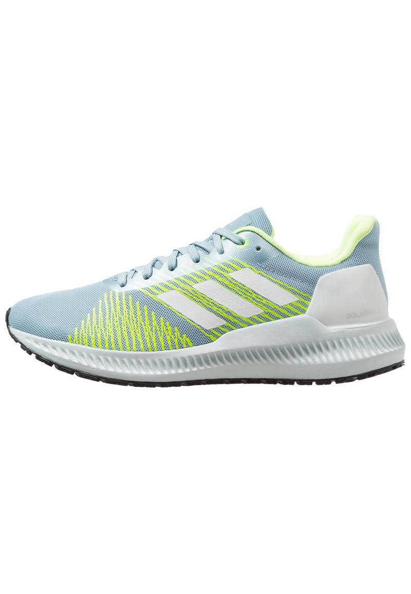 Scarpe da ginnastica blu chiaro con design a righe bianche e giallo neon, materiale in rete, suola segmentata e collo imbottito per il comfort.