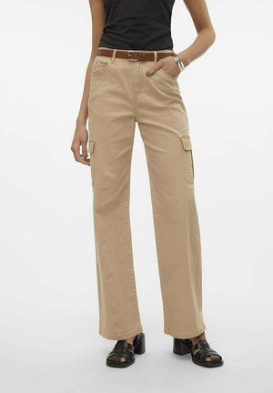 Pantalon cargo beige avec une coupe ample, deux poches latérales et une ceinture. Associé à un haut noir et des talons noirs à lanières pour le contraste.
