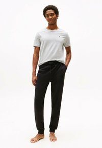 Camiseta gris de cuello redondo con mangas cortas, combinada con pantalones jogger negros ajustados que cuentan con una cinturilla elástica y puños.