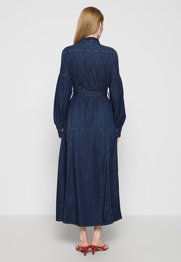 Czarna dżinsowa sukienka maxi z paskiem w talii, długimi bufkami i guzikami przy mankietach. Charakteryzuje się smukłą sylwetką i kontrastowymi szwami.