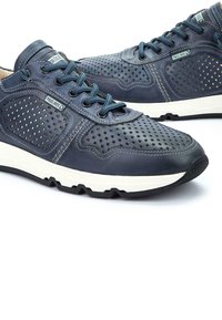 Zapatillas de cuero azul marino con diseño perforado, mediasuela blanca y suela de goma oscura. Incluye cordones a juego y etiqueta de la marca en el lateral.