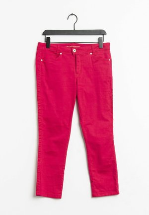 Czerwone spodnie o dopasowanym kroju z przednimi kieszeniami i zapięciem na guzik, zawieszone na czarnym plastikowym wieszaku na białym tle.