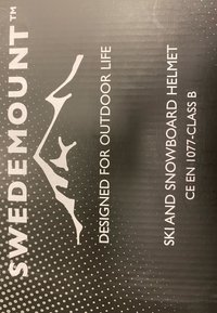 Sort emballage med hvid tekst og prikket mønster, der viser "SWEDEMOUNT," "Ski- og snowboardhjelm" og en bjerggrafik.