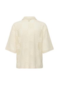 Chemise crème à manches courtes avec motif en dentelle ajourée, coupe carrée et col classique, vue de dos sur fond blanc.