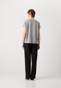 Grijze top met korte mouwen en een relaxed fit, vlakke naaddetails, gecombineerd met zwarte, rechte broek en zwarte hoge hakken.